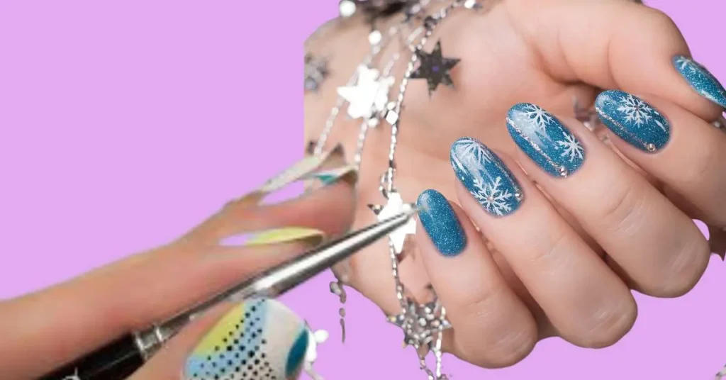 Close-up of nail art being created with a dotting tool on blue glitter nails with white snowflake details.