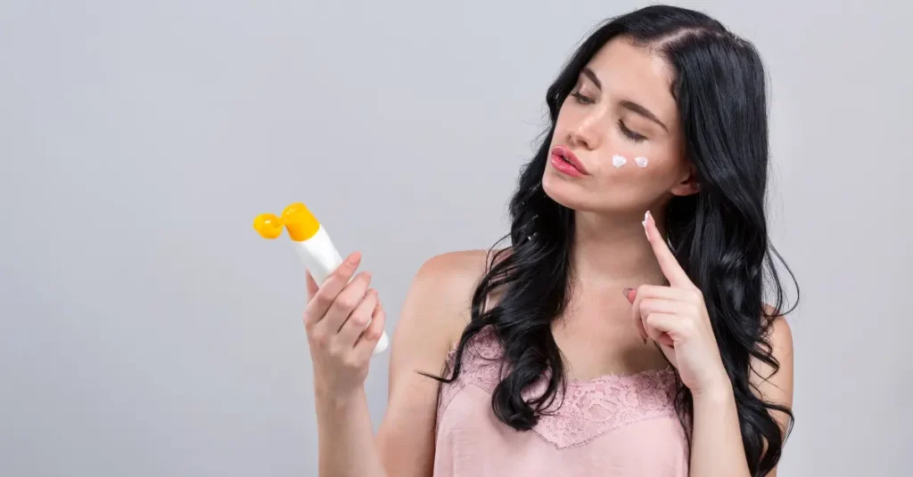 Woman dotting sunscreen on her cheeks before makeup to prevent pilling.