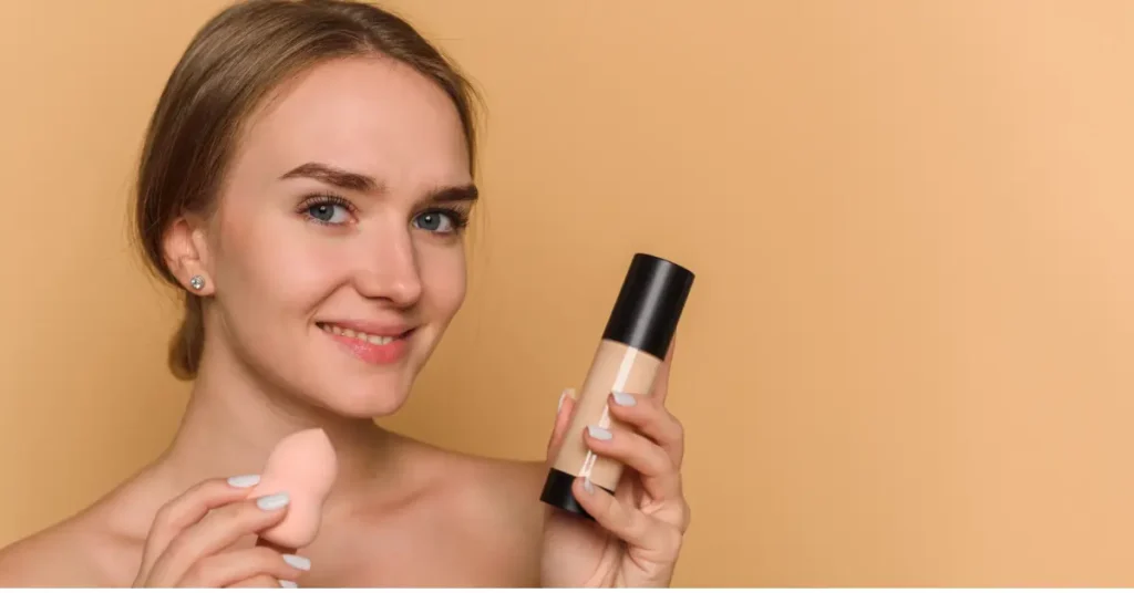 Woman holding a makeup sponge and foundation to tap base makeup over sunscreen without pilling.